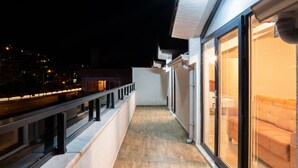 A balcony with a wooden floor and glass doors leading to a room with a sofa.