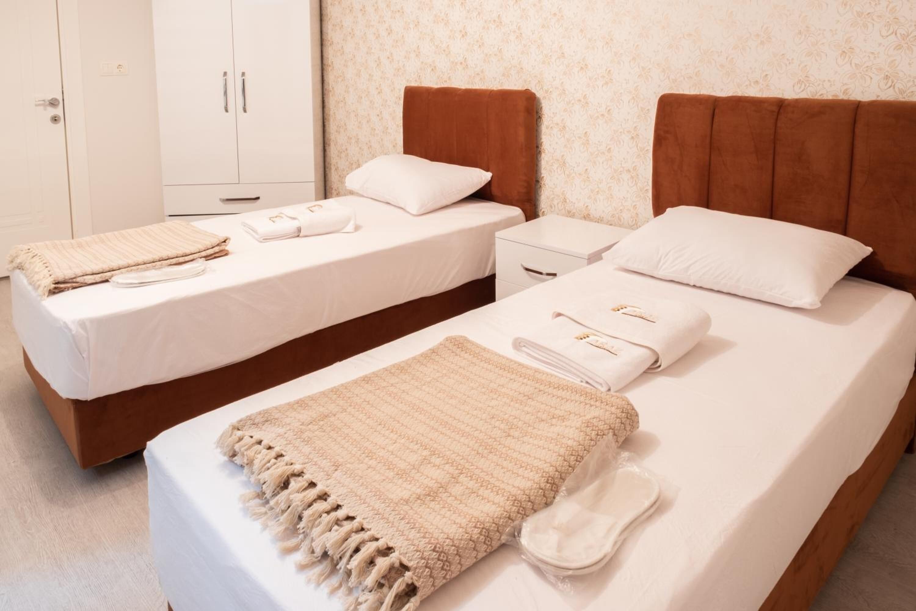 A hotel room with two single beds, a wardrobe, and a bathroom.