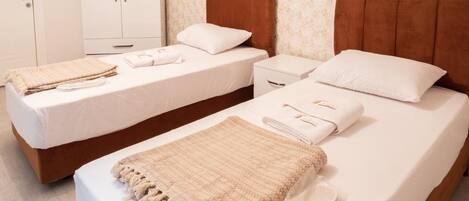A hotel room with two single beds, a wardrobe, and a bathroom.