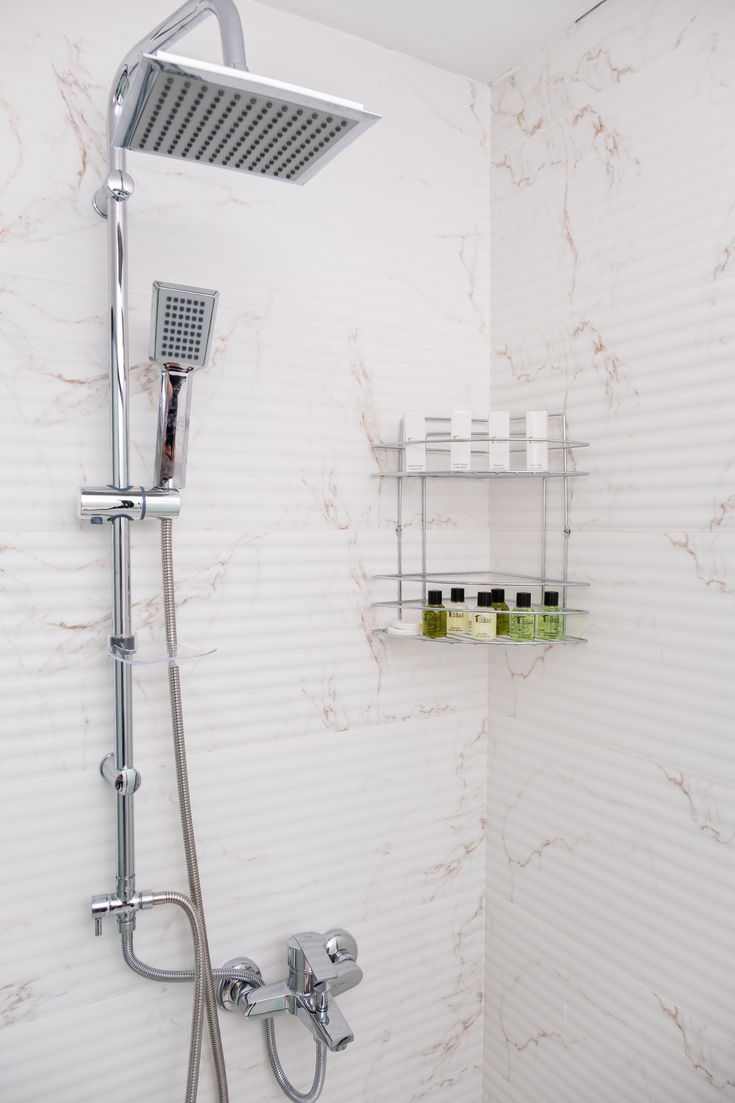 A shower with a handheld showerhead and a wall-mounted faucet.