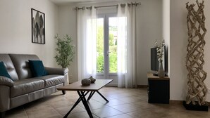 A modern living room with a leather sofa, a coffee table, a potted plant, and a decorative wall piece. - Villa, private pool (Oletta)