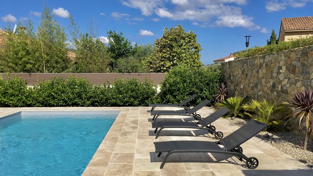 A swimming pool with lounge chairs and a stone wall. - Villa, private pool (Oletta)