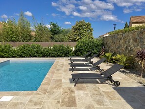 Une piscine avec des chaises longues et un mur en pierre.