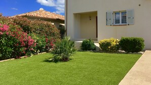 A two-story house with a well-maintained lawn and flowering bushes. - Villa, private pool (Oletta)