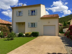 A two-story house with a garage, a well-maintained lawn, and a clear sky.