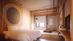 Ein schlichter Schlafzimmer mit einem großen Bett, Holzbalken, einem runden Spiegel und einem Fernseher auf einer Holzablage.