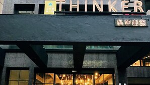 Ein modernes Gebäude mit großem Glaszugang und dem Wort "THINKER" deutlich sichtbar darüber.