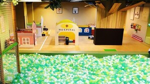 Ein Spielbereich für Kinder mit Bällebad, Rutschen und einem Spielhaus im Krankenhaus-Design.