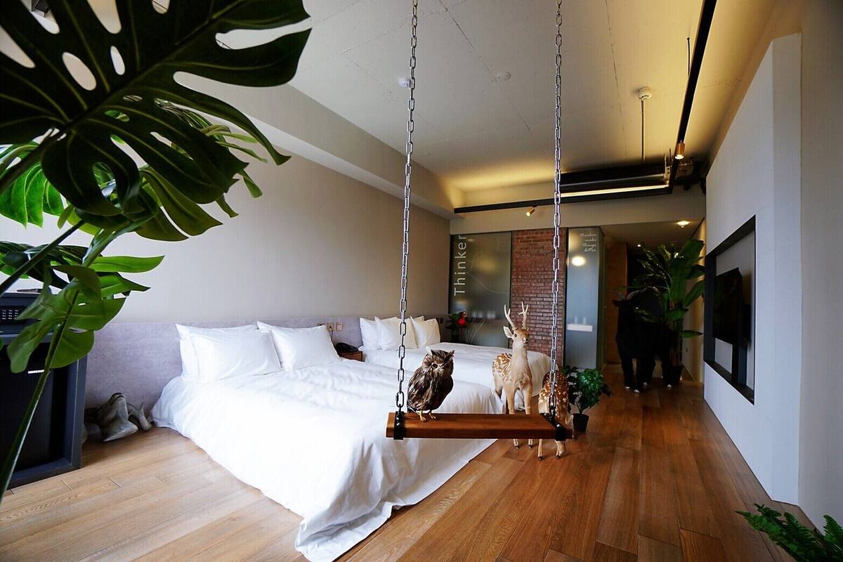 Um quarto moderno com cama, balanço suspenso e estátua de veado.
