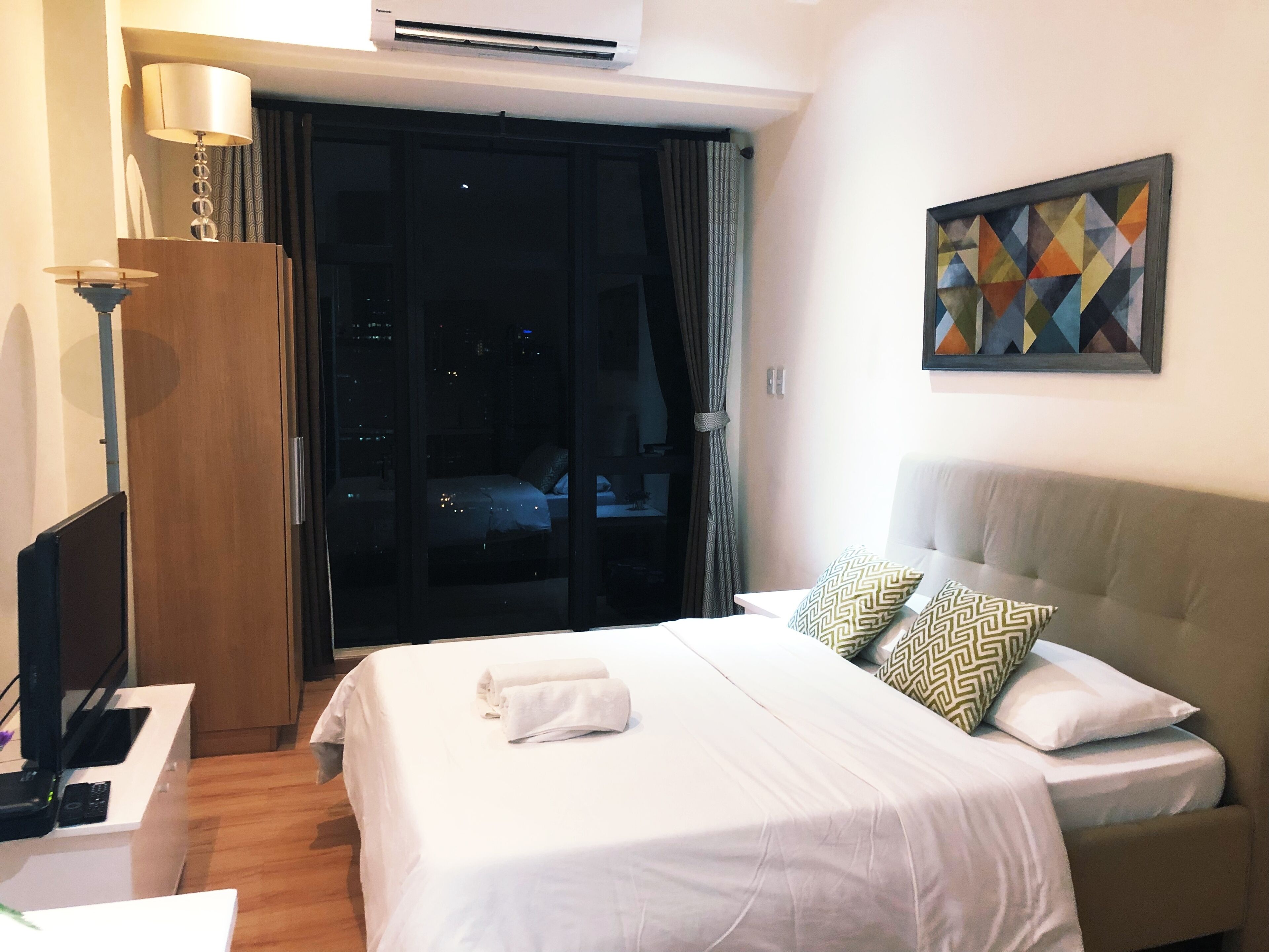 Une chambre d’hôtel avec un lit, un bureau, une lampe et un tableau au mur.