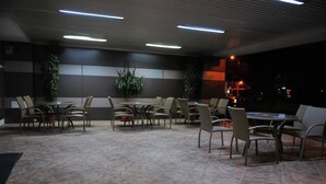 A restaurant with multiple tables and chairs, potted plants, and a tiled floor. - Hotel Emma Est (Craiova)