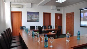 A conference room with a long table, chairs, water bottles, and a projector screen. - Hotel Emma Est (Craiova)