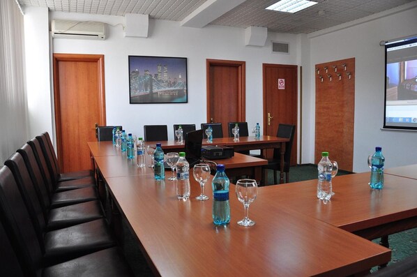 A conference room with a long table, chairs, water bottles, and a projector screen. - Hotel Emma Est (Craiova)