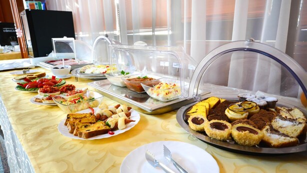 A buffet with various food items including bread, pastries, and desserts. - Hotel Emma Est (Craiova)
