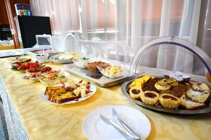 A buffet with various food items including bread, pastries, and desserts. - Hotel Emma Est (Craiova)