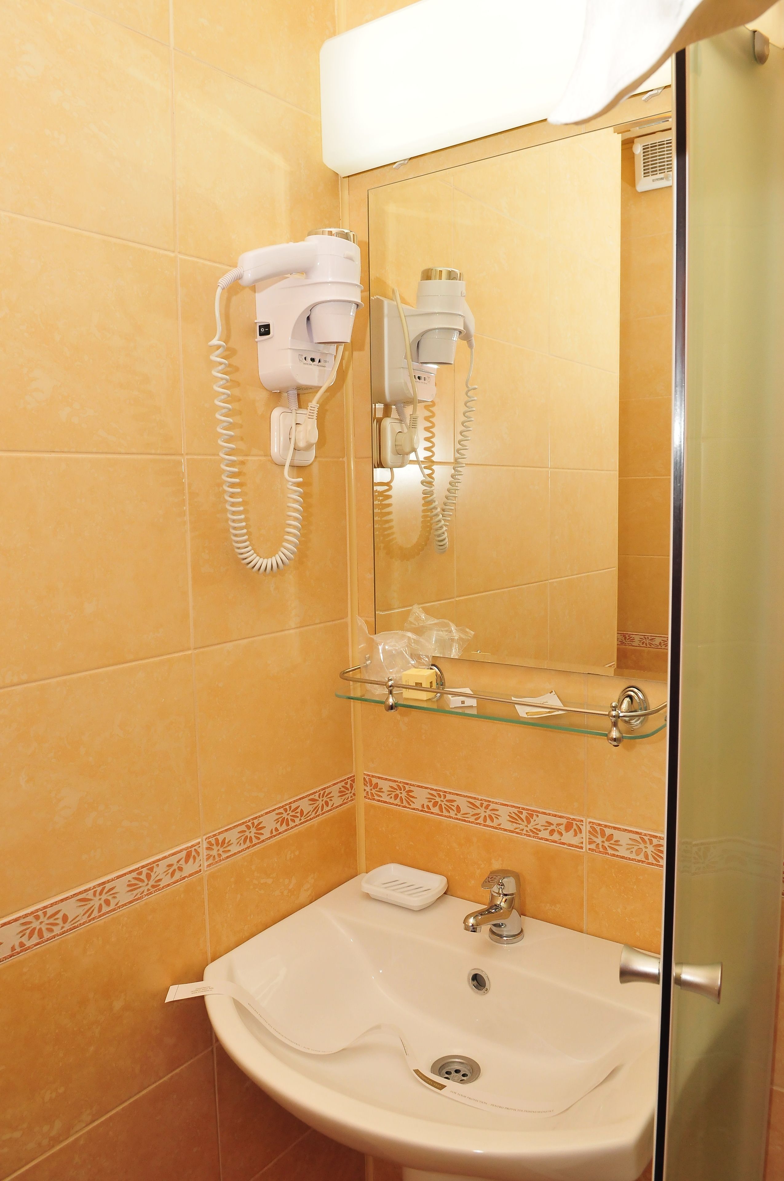 Une salle de bain équipée d’un lavabo, d’un sèche-cheveux et d’un miroir.
