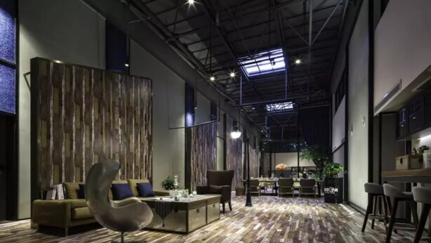 A spacious lounge area with a high ceiling, exposed beams, and a wooden floor. There are seating arrangements including a sofa and chairs, and a small table with a vase. - M Do Hotel (Weifang)