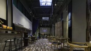 A spacious indoor area with a high ceiling, a bar area with stools, and several tables and chairs arranged for dining or socializing. - M Do Hotel (Weifang)