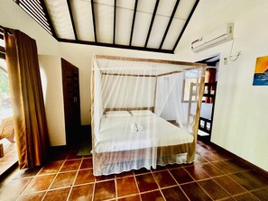 A single bed with a canopy, a tiled floor, and a ceiling fan. - Hotel Riva Del Sole (Pottuvil)