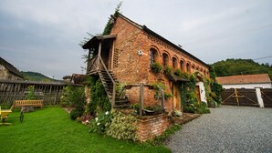 A rustic brick building with a wooden staircase leading to a loft, surrounded by a well-maintained garden and a gravel driveway. - Country House Stara Kapela (Nova Kapela)