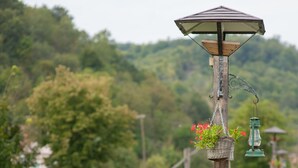 A wooden lamp post with a lantern base and a hanging basket of flowers. - Country House Stara Kapela (Nova Kapela)