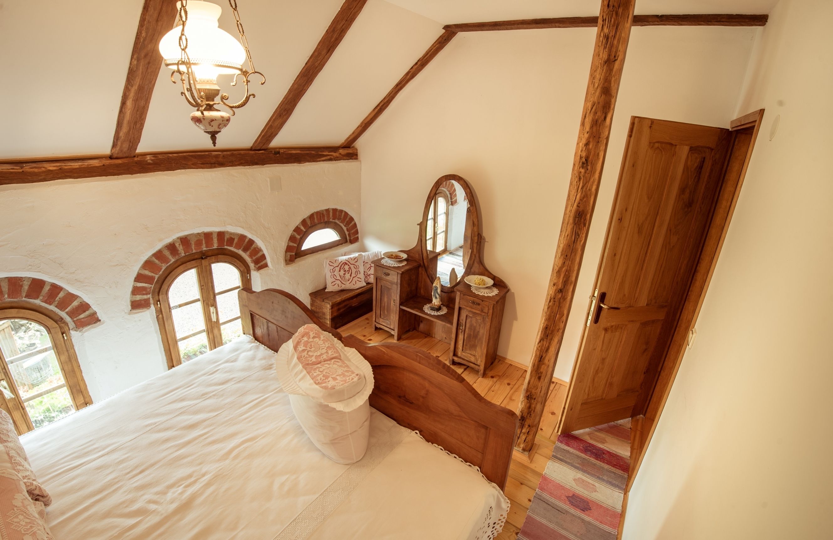 Un dormitorio con cama de madera, cómoda, espejo y una puerta.