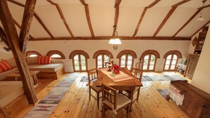 A rustic room with a wooden table, benches, and a sofa. There are arched windows and a wooden ceiling. - Country House Stara Kapela (Nova Kapela)