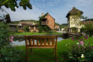 A rustic village scene with a wooden bench, a pond, and traditional houses. - Country House Stara Kapela (Nova Kapela)