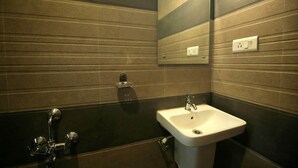 Un baño con un lavamanos blanco, un espejo y un toallero.
