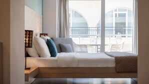 A modern hotel room with a sofa bed, a bedside table, a lamp, and a view of the balcony. - Sette Suites & Rooms - Adults Only (Xylokastro-Evrostina)