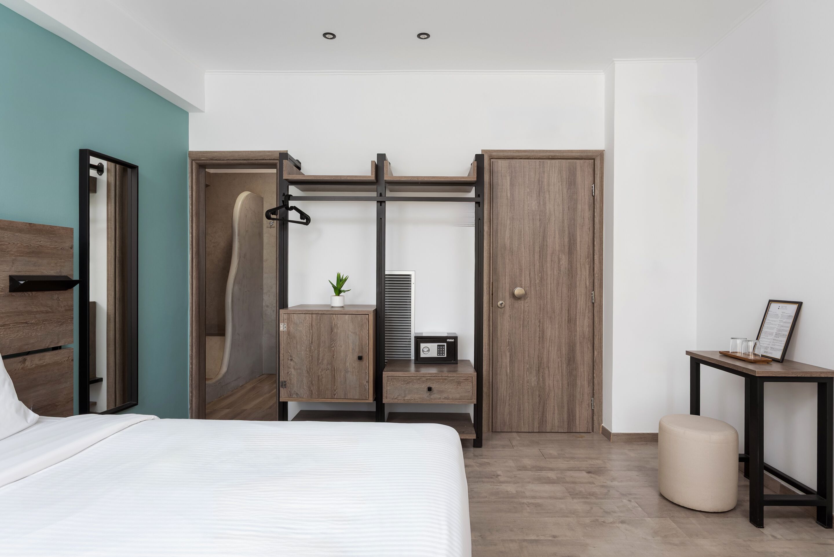 A modern bedroom with a bed, a wardrobe, a bedside table, a small stool, and a nightstand.