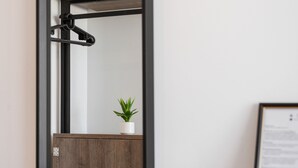 Une pièce de taille modeste, dotée d’une armoire à miroir, d’une petite plante en pot et d’une table en bois avec un verre.