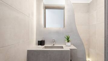 A modern bathroom with a large mirror, a sink, and a potted plant.