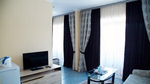 Un soggiorno con televisione, tavolino, divano e tappeto decorato.