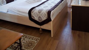 Una camera d'albergo con un letto, una scrivania, un condizionatore d'aria e una finestra con tende.