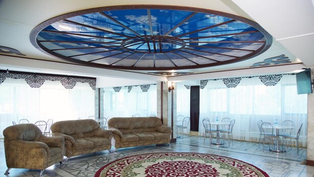 Un'ampia hall con tappeto decorato, posti a sedere confortevoli e un design del soffitto originale.