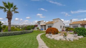A well-maintained garden with a stone pathway leading to a house with a tiled roof and white walls. - Lucy Moraira House for 6 people (Moraira)