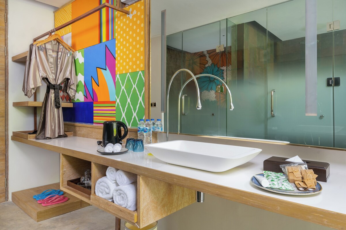 A modern bathroom with a large mirror, a white sink, and a glass shower enclosure.