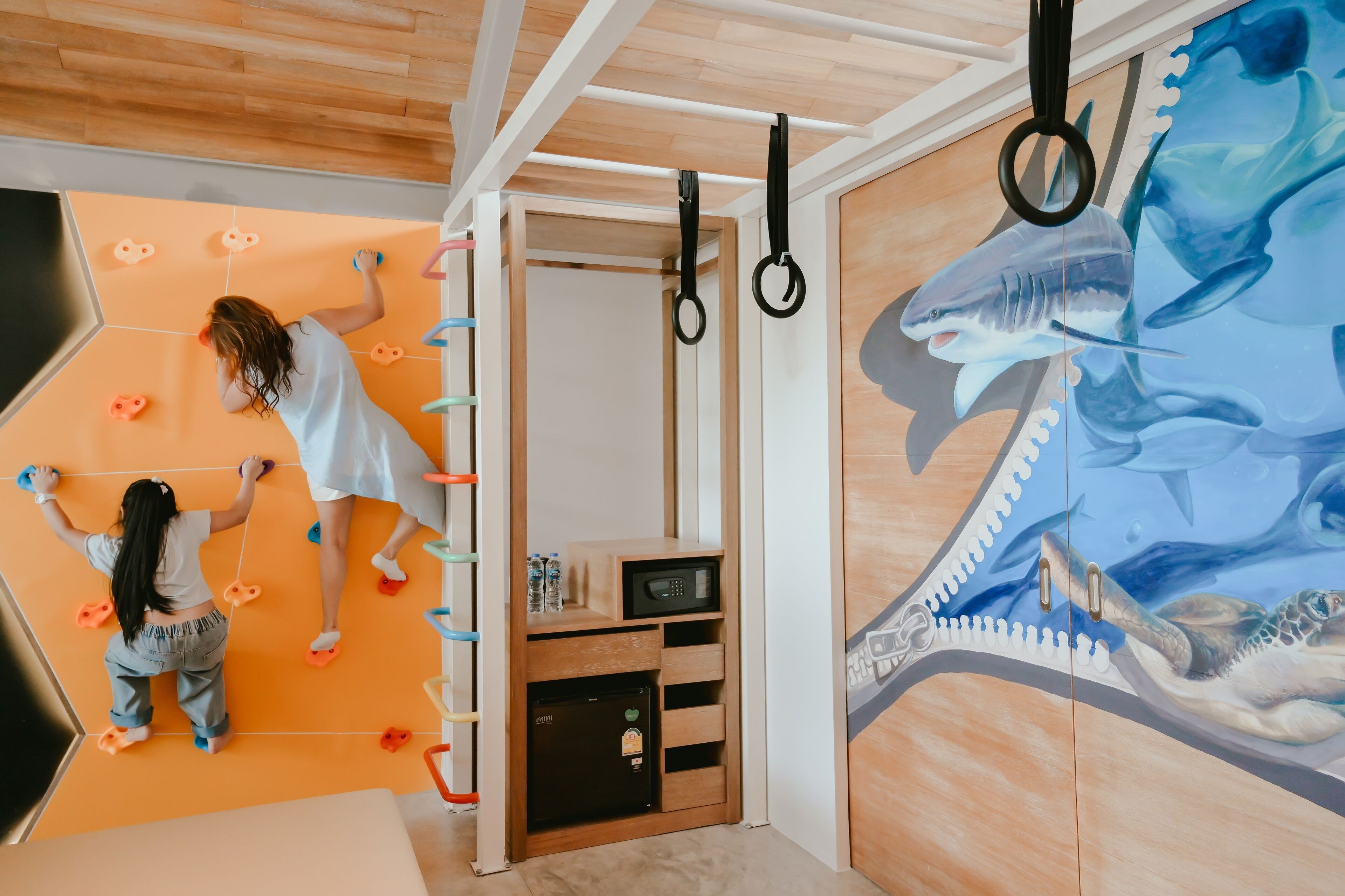 A climbing wall with various holds and a mural of a shark and turtle.