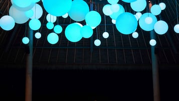 A large indoor space with a high ceiling, featuring numerous spherical light fixtures in blue and yellow.