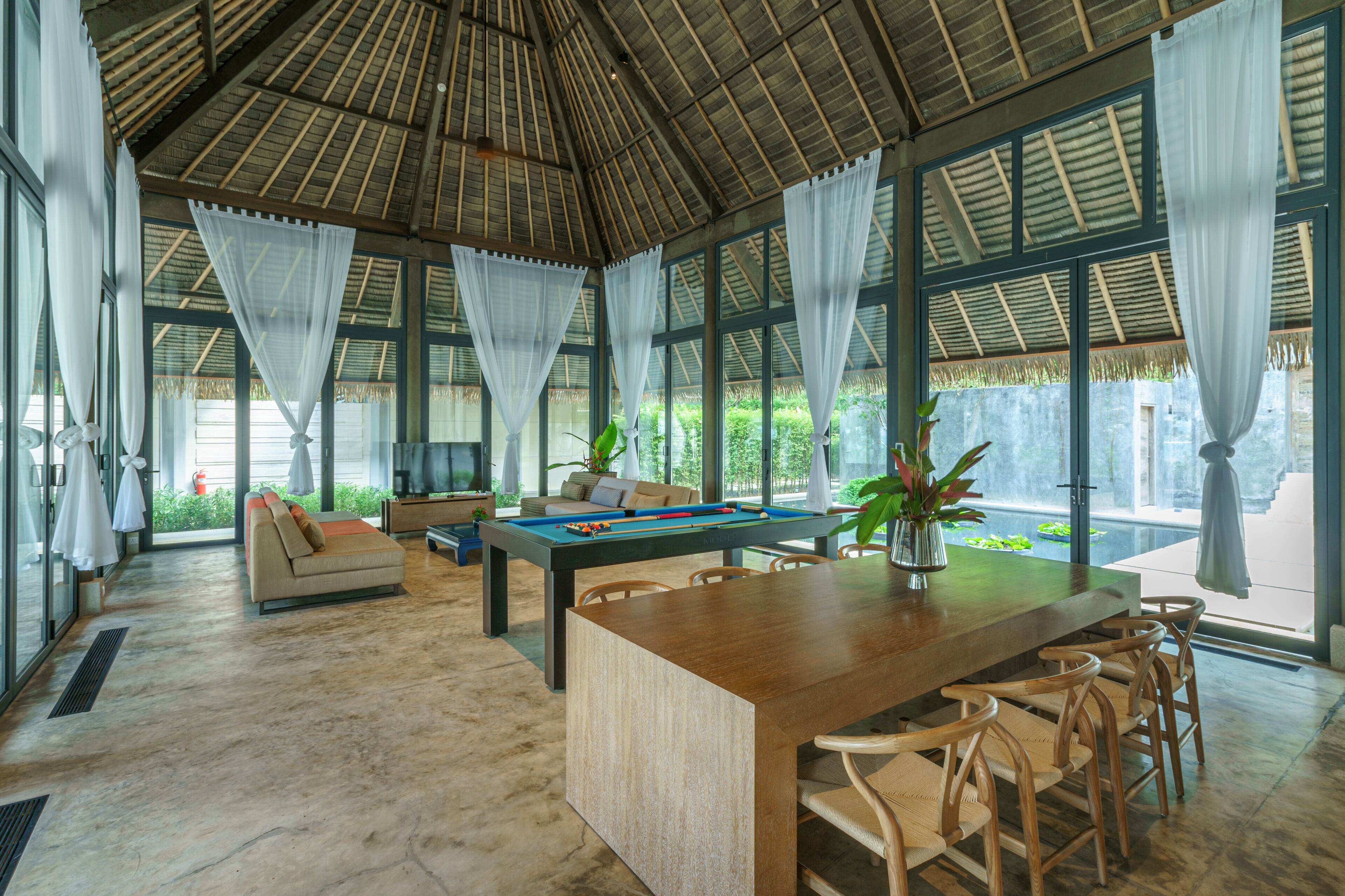 Un espacio interior amplio con mesa de billar, asientos cómodos y ventanas grandes.