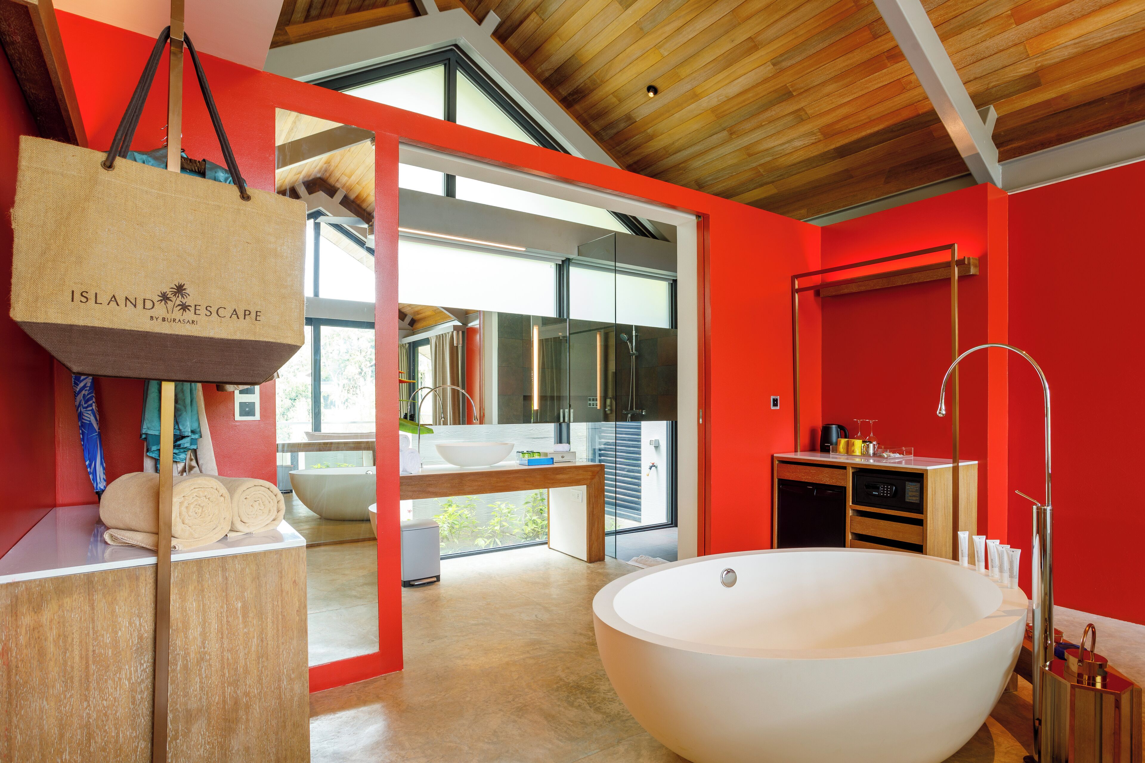 Ein modernes Badezimmer mit einer großen Badewanne, einem hölzernen Waschtisch und einer leuchtend roten Wand.