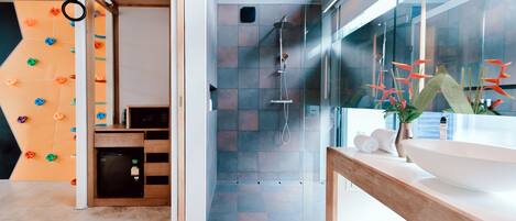 A modern bathroom with a glass shower, a wooden vanity, and a climbing wall.