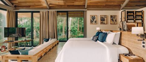 A spacious bedroom with a large bed, wooden ceiling, and a view of the outdoors through large windows.