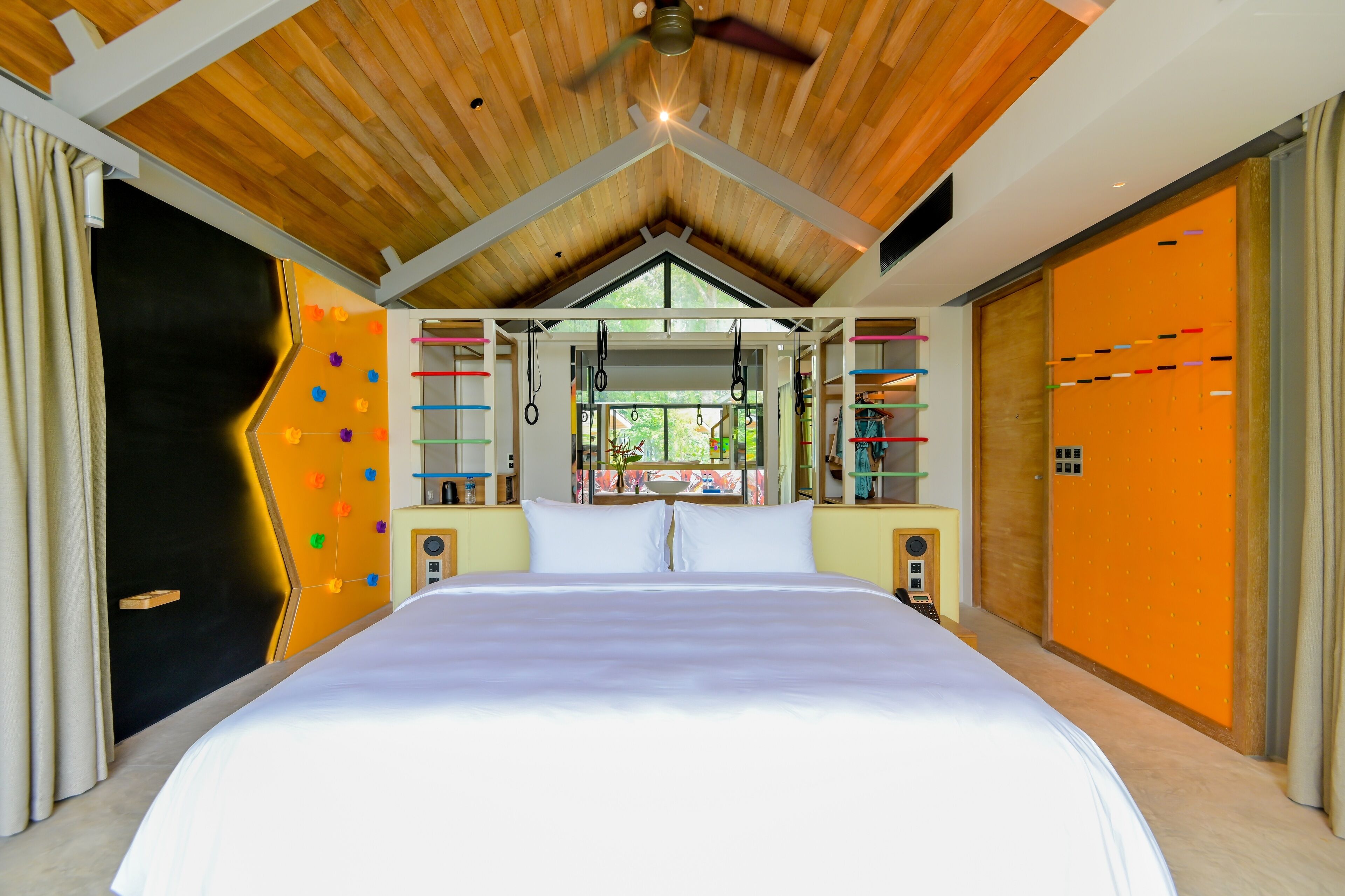 A modern bedroom with a large bed, wooden ceiling, and a view of the outdoors.