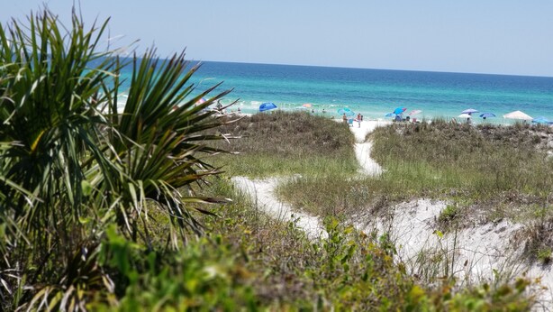 Ein Strand mit freiem Blick auf den Ozean, ein Sandweg zum Wasser und Strandstühle.