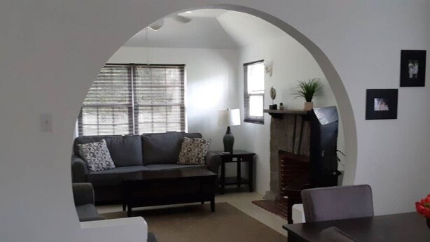 A living room with a sofa, a coffee table, a fireplace, and a dining area with a table and chairs. - Cozy stand alone cottage with Bermuda Character  (St.George's, Bermuda)