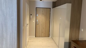 A hallway with a wooden door, a small table, and a light fixture. - ApartmentSun Parrot (Wroclaw)