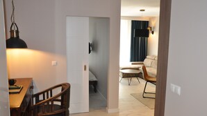 A modern living room with a sofa, a coffee table, and a dining area with a table and chairs. - ApartmentSun Parrot (Wroclaw)