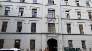A multi-story building with a symmetrical facade, large windows, and a central entrance with an arch. - ApartmentSun Parrot (Wroclaw)